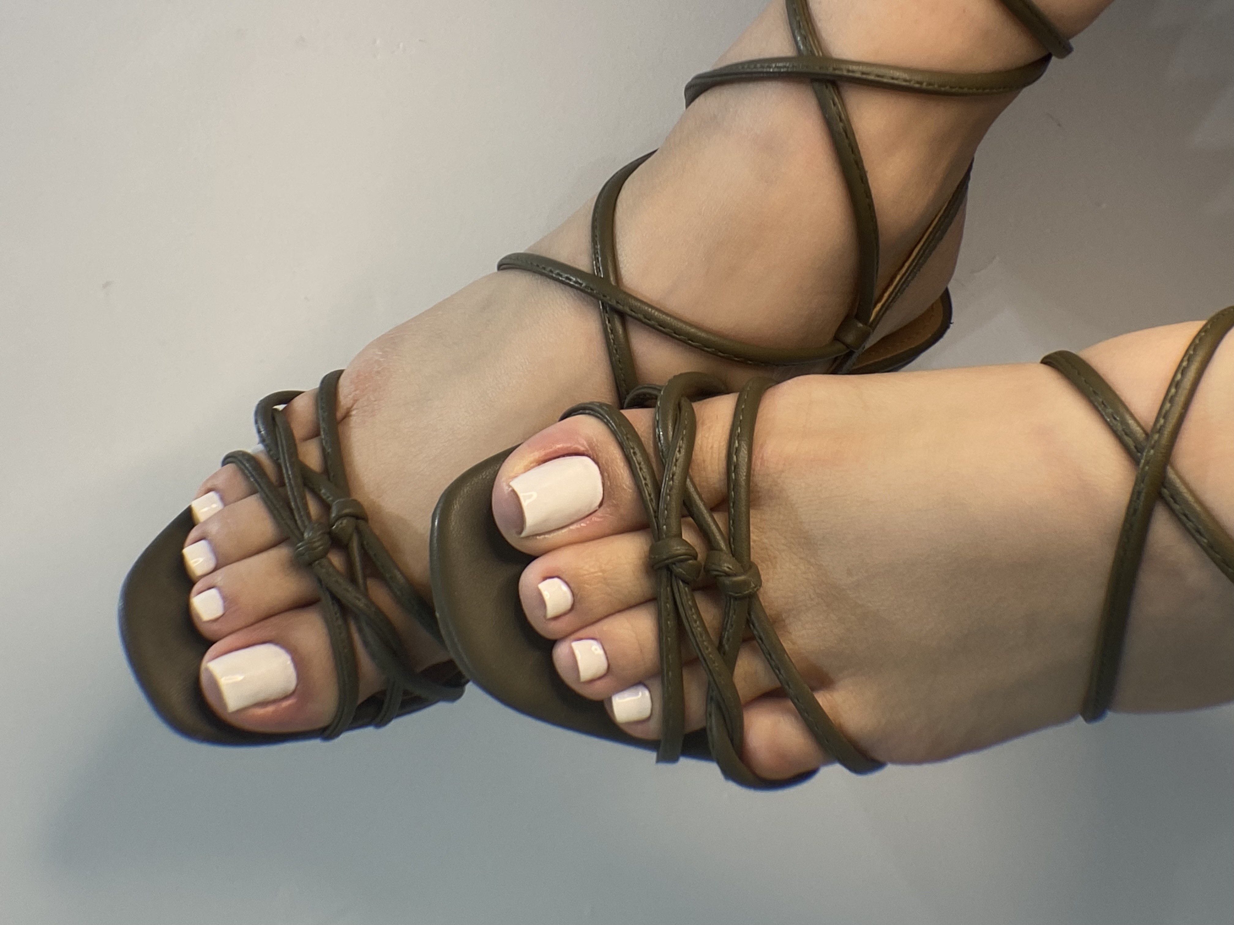 Pedicuría con esmaltado blanco y sandalias de tiras